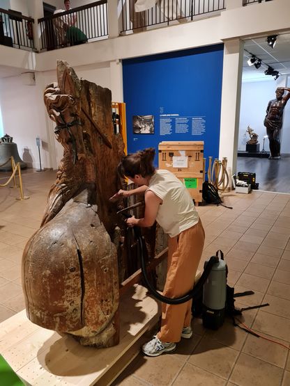 Restauratrice en train de dépoussiérer la figure de proue du Neptune avant son départ en prêt, au musée national de la Marine à Toulon.